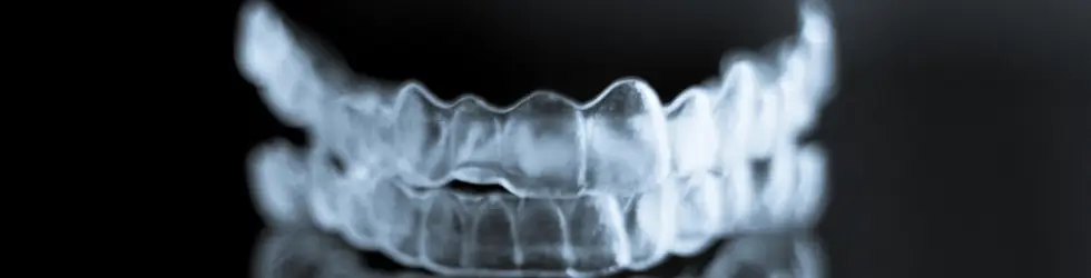 ¿Cuánto cuesta la ortodoncia invisible en Carabanchel? Precios y qué incluye el tratamiento? Alineadores transparentes sobre un fondo negro