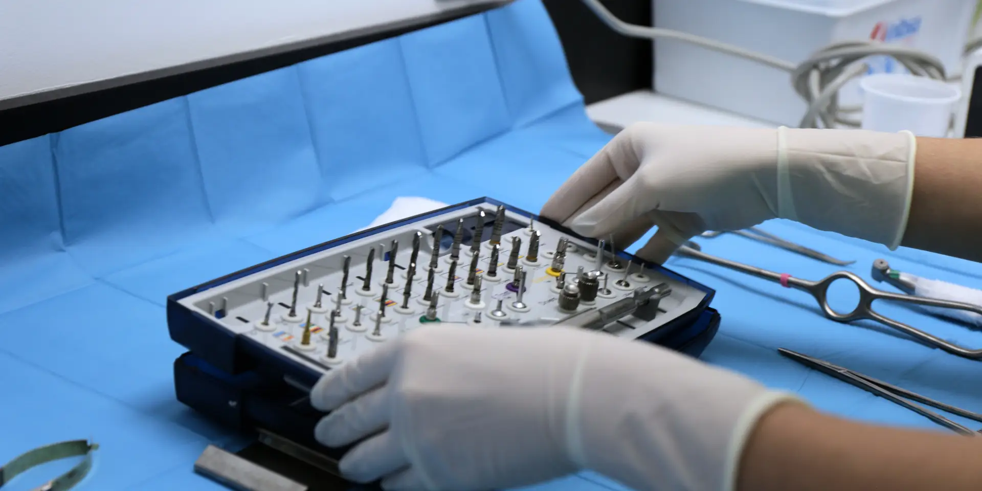 Dentista en Carabanchel colocando con precisión el material de implantología en la mesa de quirófano