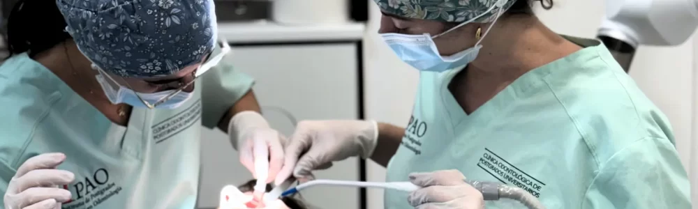 Dos odontólogos de la Clínica Odontológica de Postgrados Universitarios realizando una cirugía de implantes dentales en Vallecas bajo supervisión académica
